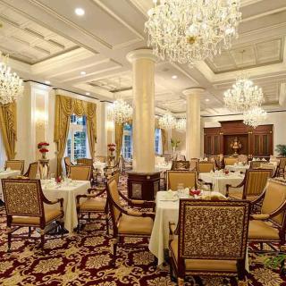 An elegant dining room with chandeliers and classic decor, featuring beautifully set tables in a luxurious setting.