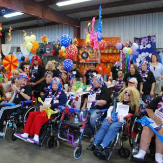 A joyful gathering of individuals in wheelchairs, celebrating together in a colorful decorated venue.