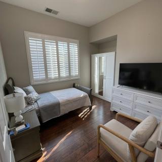 A minimalist bedroom with a bed, television, and large window letting in natural light.
