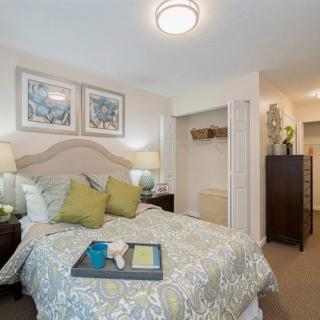 A cozy bedroom with stylish decor, featuring a neatly made bed, artwork above the headboard, and a small closet.