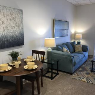 A modern living room with a cozy sofa, dining table set for four, and tasteful artwork on the walls.