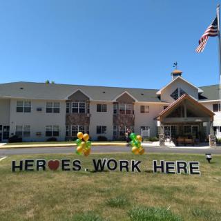 A building with a sign reading 'HEROES WORK HERE' and balloons on the lawn.