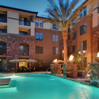 An apartment complex with a beautifully lit swimming pool in the evening.
