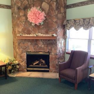 A cozy living room featuring a stone fireplace, floral decor, and a comfortable armchair.