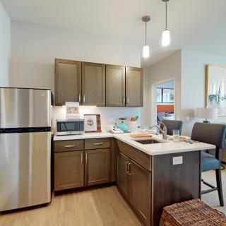 A modern kitchen featuring stainless steel appliances, sleek cabinets, and a central island with bar stools.