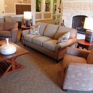 A cozy living room with a sofa, armchairs, and a fireplace.