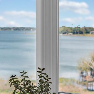 A peaceful lakeside view through a window with a plant on the sill.