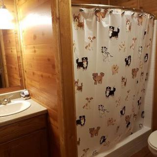 A cozy bathroom with wood paneling and a dog-themed shower curtain.