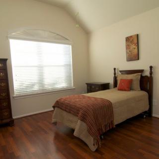 A cozy bedroom with a single bed and wooden flooring.