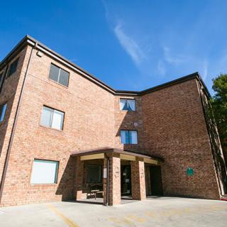 A brick apartment building with a main entrance and blue sky in the background.