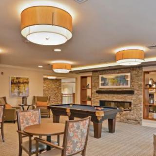 A cozy lounge area featuring a billiards table, comfortable seating, and warm lighting.
