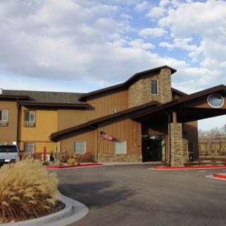 A hotel building with a modern design and stone accents, set against a partly cloudy sky.
