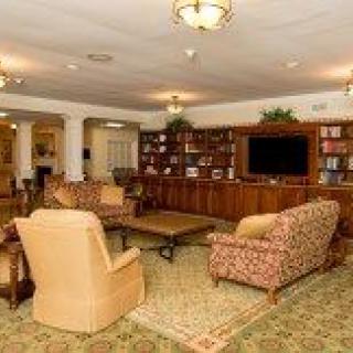 A cozy living room featuring comfortable seating, a large bookshelf, and a television.