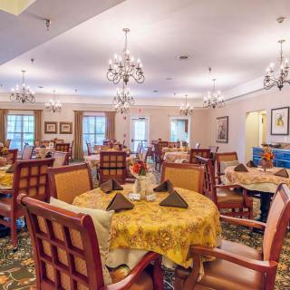 Elegant dining room with tables set for guests and adorned with chandeliers.