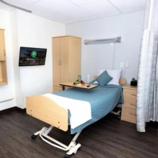 A modern hospital room with a single bed and essential furnishings.