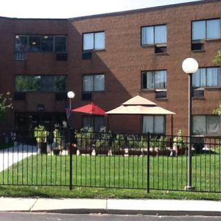 A modern residential building with outdoor seating areas and a well-maintained lawn.