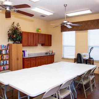 A well-organized conference room with a large table, chairs, cabinets, and a bookshelf.