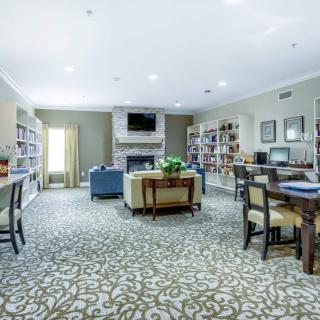 A cozy library space with bookshelves, comfortable seating, and a fireplace.