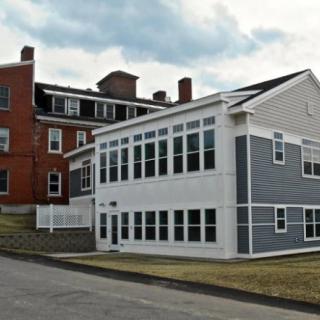 A residential building featuring a brick structure with a modern extension and numerous windows.