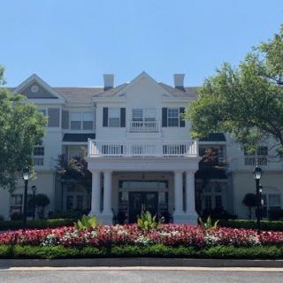 A large building with a grand entrance, surrounded by well-maintained landscaping and vibrant flowers.