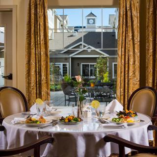 A beautifully set dining table by a window with an elegant outdoor view.