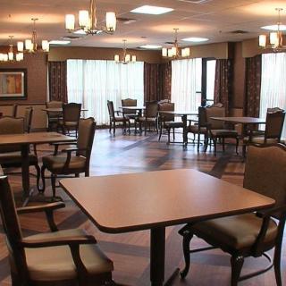 A spacious dining area with arranged tables and chairs, illuminated by overhead lights.