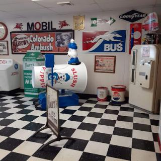 A nostalgic display of vintage gas station memorabilia featuring colorful signs and a checkered floor.