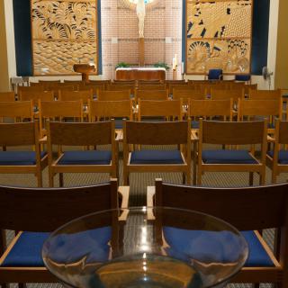 Interior view of a chapel with rows of chairs facing the altar.