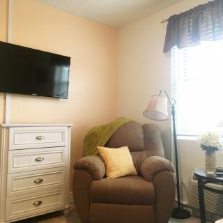 A cozy living room corner with an armchair, television, and dresser.