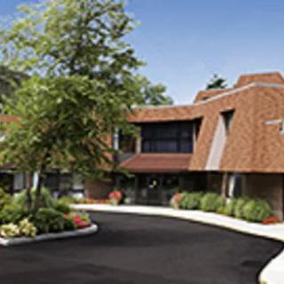 A modern office building with a landscaped driveway and trees.