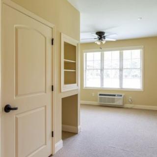 Empty room with carpeted floor, a door, and a window with an air conditioner.