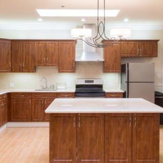 A modern kitchen with wooden cabinets, a central island, and stainless steel appliances.