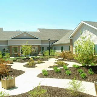 A beautifully landscaped building with pathways and greenery in a sunny environment.