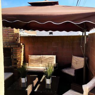 A cozy outdoor patio setup with seating and a large umbrella providing shade.