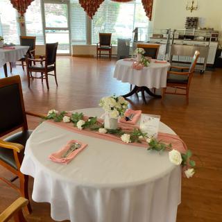 A beautifully decorated dining room set up with round tables featuring pink and white floral arrangements.