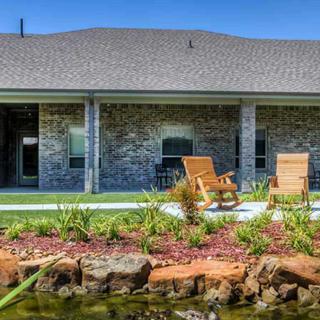 A cozy backyard patio with wooden rocking chairs and a landscaped garden.