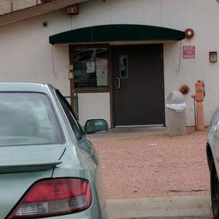 A view of a building entrance with a parked car nearby.