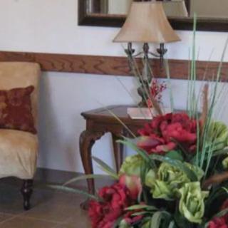 A cozy room corner featuring a comfortable chair, a wooden side table with a lamp, and a vibrant bouquet of flowers.