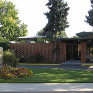 A modern brick house with well-maintained landscaping and surrounding trees.