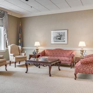 A traditional living room featuring elegant furniture, including a sofa, chairs, a wooden coffee table, and lamps.