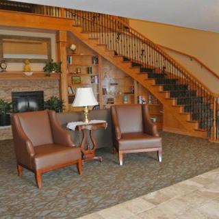 A cozy lobby area featuring two leather chairs, a small table with a lamp, and a wooden staircase.