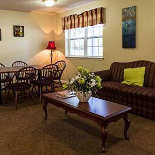 A cozy living room with a dining area, featuring a sofa, coffee table, and a dining set next to a window.