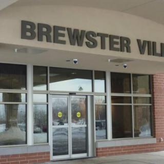Entrance of Brewster Village with glass doors and signage.