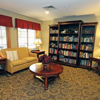 A cozy reading room with a bookshelf, sofa, and a table.