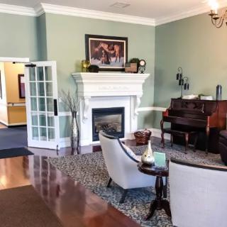 A cozy living room with a fireplace, piano, and comfortable seating.