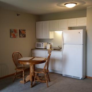 A small kitchen and dining area with a table, chairs, refrigerator, and microwave.