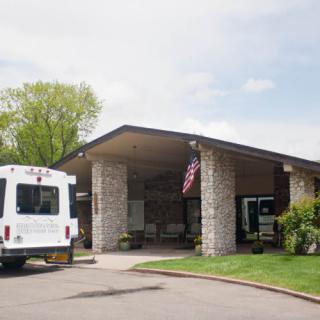 A building entrance with a parked van and an American flag.
