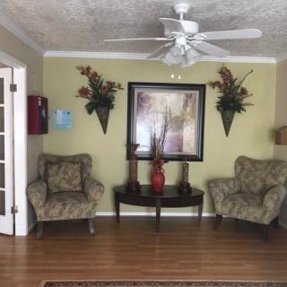 A cozy living room with two patterned chairs, a central table, and decorative wall elements.