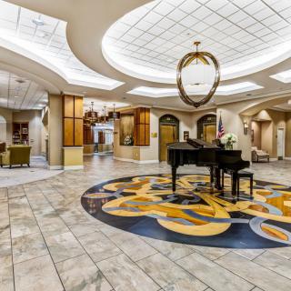 A luxurious hotel lobby with an elegant grand piano and a stunning chandelier.