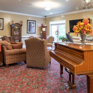 A cozy living room with comfortable seating, a piano, and elegant decor.